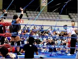 青い紙テープがリングを舞い、選手が手を挙げてピースをしている写真